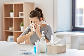 Image showing sick woman with medicine blowing nose to wipe