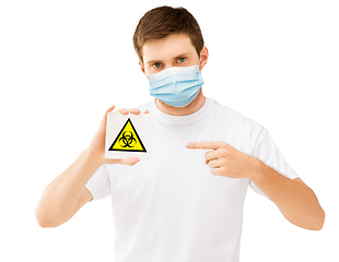 Image showing man in medical mask holding boihazard caution sign