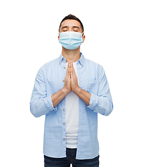 Image showing young man in protective medical mask praying