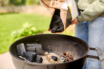 Image showing close up of man pouring charcoal to brazier