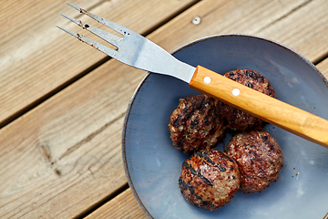 Image showing roasted meat cutlets on plate with barbeque fork