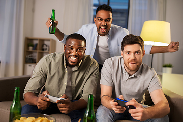 Image showing happy friends playing video games at home at night