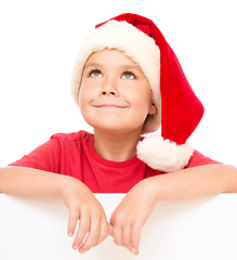 Image showing Little girl in santa hat is holding blank board