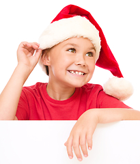 Image showing Little girl in santa hat is holding blank board