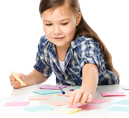 Image showing Girl is writing on color stickers using pen