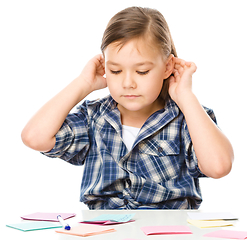 Image showing Girl is writing on color stickers using pen