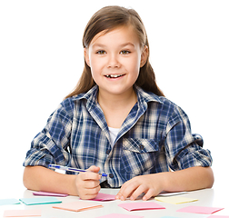 Image showing Girl is writing on color stickers using pen