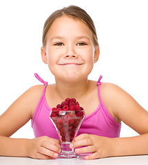 Image showing Happy little girl is eating raspberries