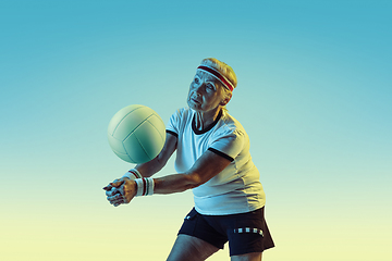 Image showing Senior woman training in volleyball in sportwear on gradient background in neon light