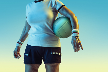 Image showing Senior woman training in volleyball in sportwear on gradient background in neon light