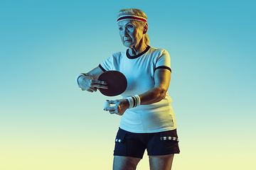 Image showing Senior woman training in table tennis in sportwear on gradient background in neon light