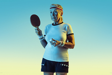 Image showing Senior woman training in table tennis in sportwear on gradient background in neon light