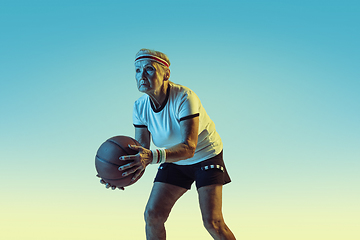 Image showing Senior woman playing basketball in sportwear on gradient background in neon light