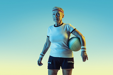 Image showing Senior woman training in volleyball in sportwear on gradient background in neon light