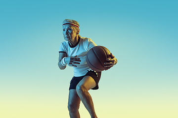 Image showing Senior woman playing basketball in sportwear on gradient background in neon light