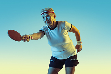 Image showing Senior woman training in table tennis in sportwear on gradient background in neon light