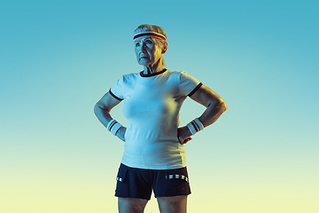 Image showing Senior woman training and posing in sportwear on gradient background in neon light