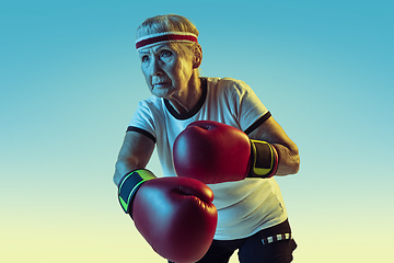 Image showing Senior woman boxing in sportwear on gradient background in neon light