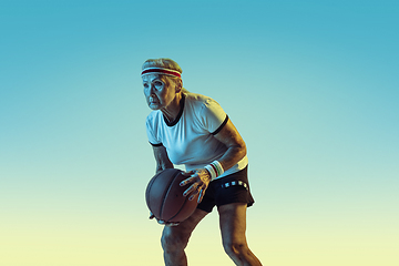Image showing Senior woman playing basketball in sportwear on gradient background in neon light