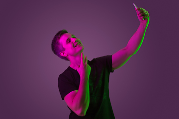 Image showing Caucasian man\'s portrait isolated on purple studio background in neon light