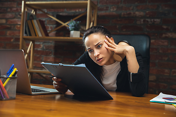 Image showing Young woman working in modern office using devices and gadgets. Making reports, analitycs, routine processing tasks