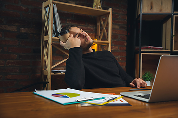 Image showing Young man working in modern office using devices and gadgets. Making reports, analitycs, routine processing tasks