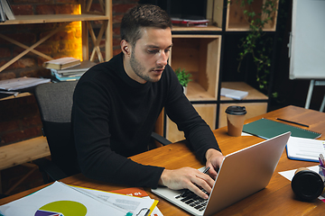 Image showing Young man working in modern office using devices and gadgets. Making reports, analitycs, routine processing tasks