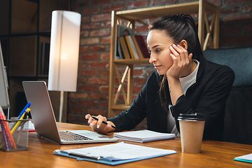 Image showing Young woman working in modern office using devices and gadgets. Making reports, analitycs, routine processing tasks