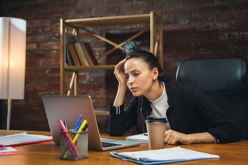 Image showing Young woman working in modern office using devices and gadgets. Making reports, analitycs, routine processing tasks