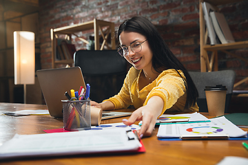 Image showing Young woman working in modern office using devices and gadgets. Making reports, analitycs, routine processing tasks