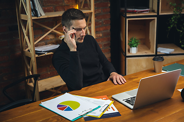 Image showing Young man working in modern office using devices and gadgets. Making reports, analitycs, routine processing tasks