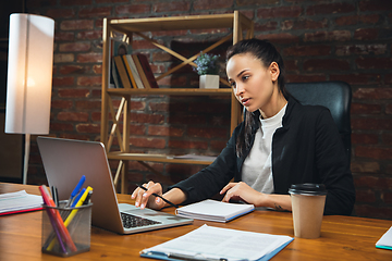 Image showing Young woman working in modern office using devices and gadgets. Making reports, analitycs, routine processing tasks