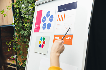 Image showing Close up hands of people, managers working in modern office using modern devices and flipchart with graphics