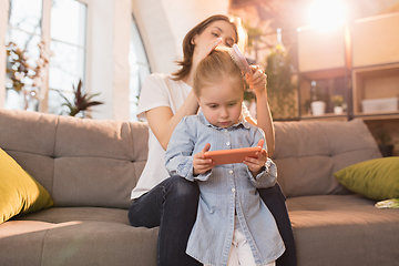 Image showing Family time. Mother and daughter having time together at home, look happy and sincere