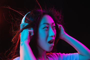 Image showing Asian young woman\'s portrait on dark studio background in neon. Concept of human emotions, facial expression, youth, sales, ad.