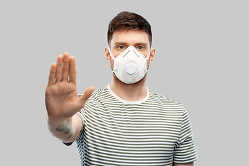 Image showing man in respirator mask making stop gesture