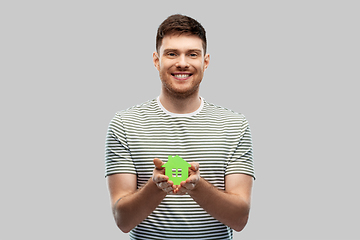 Image showing smiling young man holding green house icon