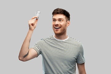 Image showing smiling young man holding lighting bulb