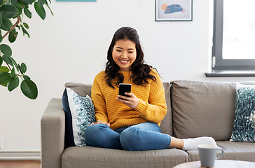 Image showing happy asian young woman with smartphone at home