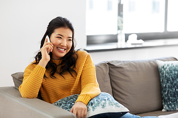 Image showing smiling asian woman calling on smartphone at home