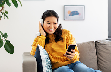 Image showing asian woman with headphones and smartphone at home