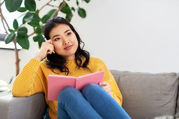 Image showing asian woman with diary sitting on sofa at home