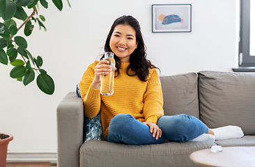 Image showing smiling asian young woman drinking water at home