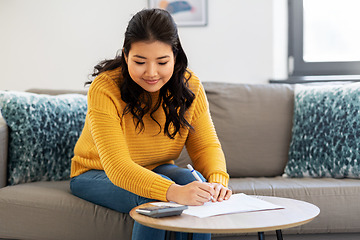 Image showing asian woman with papers and calculator at home