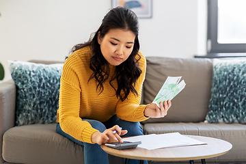 Image showing woman with money, papers and calculator at home