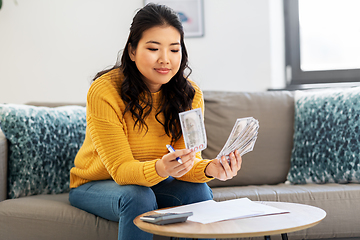 Image showing woman with money, papers and calculator at home