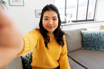 Image showing smiling asian young woman taking selfie at home