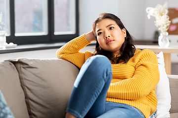 Image showing worried asian young woman sitting on sofa at home