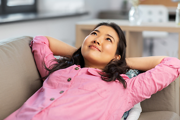 Image showing asian woman lying on sofa and dreaming at home