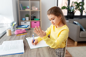 Image showing student girl with book writing to notebook at home